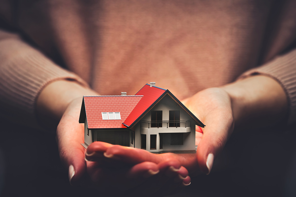 Person holding a small house in their hands to show care and love.