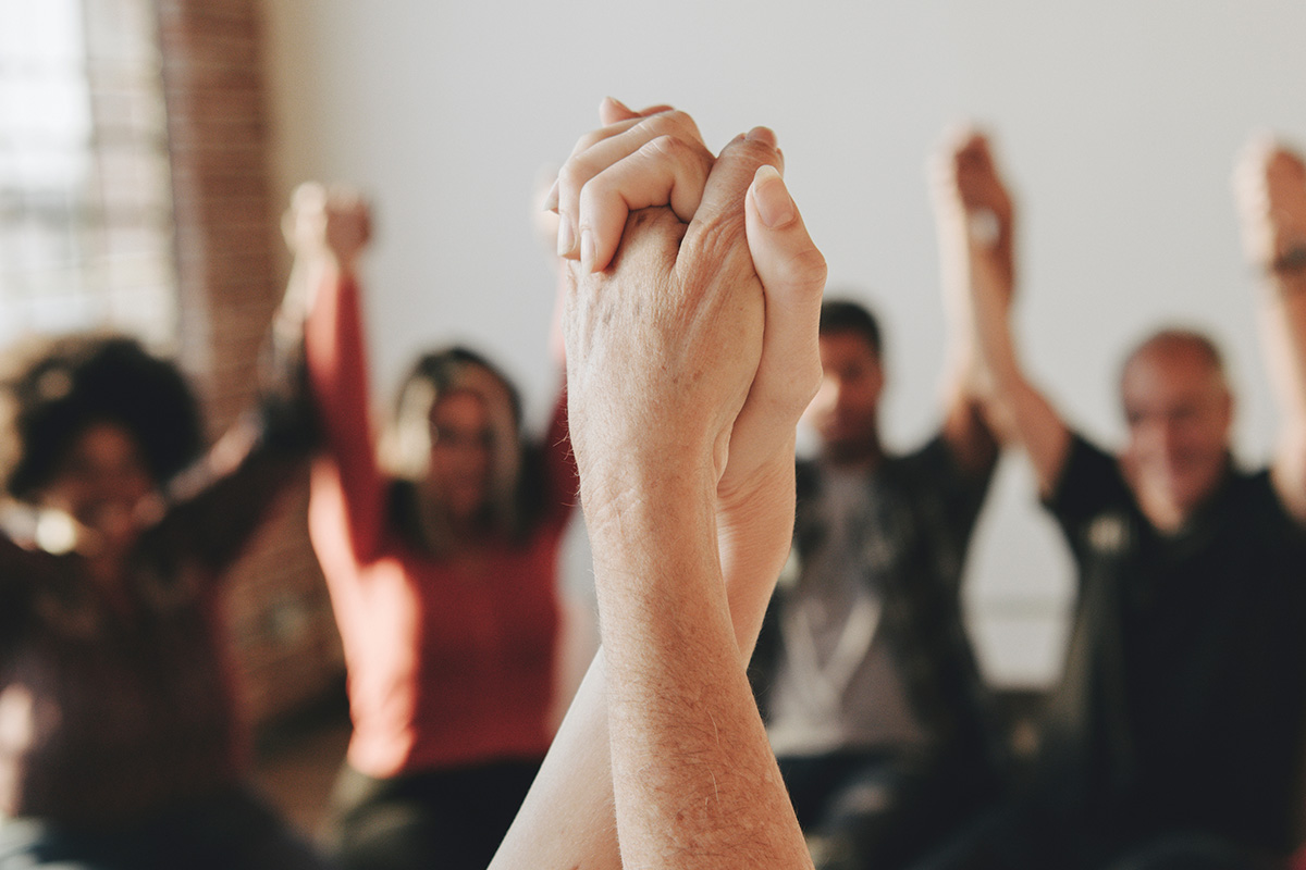 Group of people holding hands in a group therapy session.